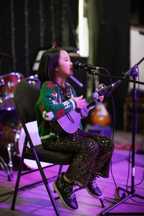 A young student singing and playing ukulele in a solo act